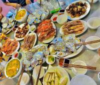 Una mesa con muchos platos de comida encima. en Cô Tô Lương Chi, en Quảng Ninh