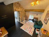 a living room with a green couch and a stone wall at Le Planzollais in Planzolles