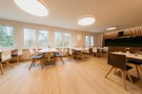 una sala da pranzo con tavoli, sedie e finestre di Bergpension Laasen Perle Rathen a Kurort Rathen