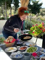 Goknar Knidos Eco Hotel & Farm في داتشا: امرأة تطبخ الطعام في مقلاة على طاولة