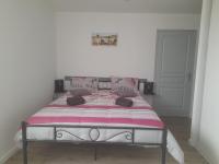 a bed with a pink and white blanket on it at Le Brait des Champs in Vinezac
