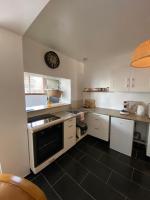 a kitchen with white cabinets and a clock on the wall at Le jardin secret in Sangatte