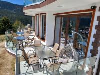 Un balcón con mesas y sillas en un patio. en Вилно селище PARADISE VIEW, en Sarnitsa