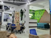 un restaurante con sillas y mesas azules y una pared verde en Вилно селище PARADISE VIEW, en Sarnitsa