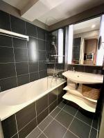 a bathroom with a bath tub and a sink at Maïa YourHostHelper in Caen