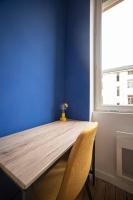 a wooden table in a room with a blue wall at LE MONDRIAN - Hôtel de ville - Confort - Paisible - Wi-Fi in Saint-Étienne