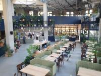 ソウルにあるJunibino Hotel Hongdaeのテーブルと椅子、背景の人々が並ぶレストラン