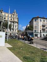 a bus on a city street with people standing near a sidewalk at Appartement atypique et original in Nice