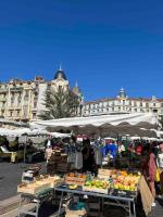 a market with fruits and vegetables on tables in front of a building at Appartement atypique et original in Nice