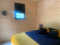 a bedroom with a bed with a television on the wall at Chalet 1 contemporain dans son écrin de verdure in Montauban
