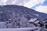a snow covered mountain with a building and a tower at La petite Anfiane in Le Grand-Bornand