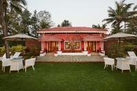 a pink house with chairs and tables in a yard at Taj Holiday Village Resort & Spa, Goa in Candolim