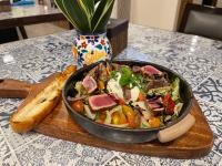 uma panela com comida sobre uma tábua de madeira, acompanhada de salada. em Serene La Playa Boracay em Boracay