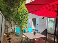 a table and chairs on a patio with a red umbrella at Le jardin de l&#39;horloge in La Rochelle