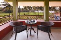 a table and two chairs on a porch with a view of the greens at Taj Holiday Village Resort & Spa, Goa in Candolim