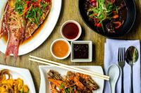 Una mesa con platos de comida y palillos y platos de comida. en L' Meridian Suites, en Zamboanga