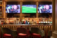 a bar with two televisions and a football game on monitors at The Cumberland, London in London