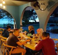 un grupo de personas sentadas alrededor de una mesa de madera en La Collina Villa, en Jepara