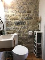 a bathroom with a white toilet and a stone wall at Le pigeonnier du beffroi in Bruniquel
