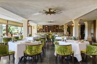 a restaurant with white tables and green chairs at Coquillade Provence - Relais & Châteaux in Gargas