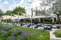 a restaurant with white tables and chairs in front of a building at Coquillade Provence - Relais & Châteaux in Gargas