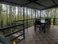 a porch with a table and chairs in the woods at Cholai Resorts & Hotels in Yercaud