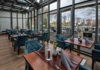 Un restaurante con mesas y sillas y grandes ventanales. en Landhotel Burg im Spreewald - Resort & Spa, en Burg