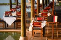 a restaurant with tables with red chairs and water at The Naka Island, a Luxury Collection Resort & Spa, Phuket in Ko Naka