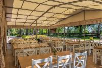een feestzaal met houten tafels en witte stoelen bij Osada Grzybowski Młyn apartamenty z dużym ogrodem KAISERÓWKA in Grzybowo