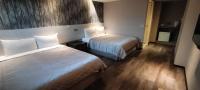 a hotel room with two beds and wooden floors at Palmer Hotel in Taichung