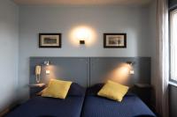 a bedroom with a blue bed with two yellow pillows at Hotel La Chope in Cambrai