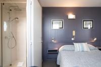 a bedroom with a blue wall with a bed and a shower at Hotel La Chope in Cambrai