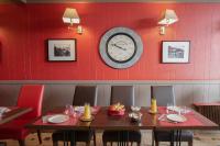 a dining room with a table and a clock on the wall at Hotel La Chope in Cambrai