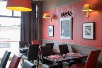 a restaurant with red walls and tables and chairs at Hotel La Chope in Cambrai