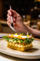 スキアトスタウンにあるSkiathos Theros, Philian Hotels and Resortsの皿の上の食べ物とフォークを持っている人