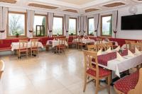 Un restaurante con mesas y sillas y un televisor de pantalla plana. en Hotel Waidachhof, en Kössen
