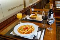 a table with a plate of pasta and a glass of wine at Rio Aeroporto Hotel Galeão in Rio de Janeiro