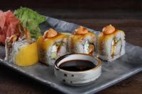 Un plato con sushi y un tazón de salsa para mojar en Torino Hotel Amman, en Amán