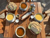 uma mesa de madeira com tigelas de sopa e sanduíches sobre ela em Complex Turistic Cetatea Drencova em Drencova