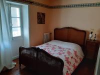 a bedroom with a bed with a floral comforter and a window at La Volière in Champigny-sur-Veude