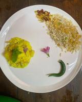 a plate of food with rice and a flower on it at Bardia Wild Side Hotel in Bhurkīā