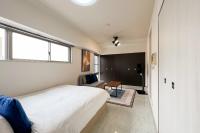 a bedroom with a bed and a chair and a table at Trioni EBISU in Osaka