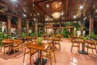 an empty restaurant with wooden tables and chairs at Suka Beach Inn in Kuta