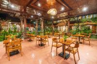 a restaurant with tables and chairs and plants at Suka Beach Inn in Kuta