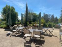 a group of tables and chairs with umbrellas at Gîte - Auberge du Midi in Saint-Antoine