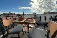 a table with a bottle of wine and two chairs on a balcony at Panorama des Chartrons in Bordeaux