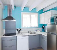 a kitchen with white cabinets and a blue wall at Village Drôles d&#39;Oiseaux in Le Teich