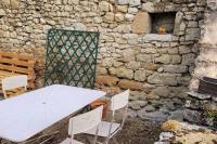 a white table and chairs next to a stone wall at Maison périgourdine avec vue et piscine chauffée in Peyzac-le-Moustier