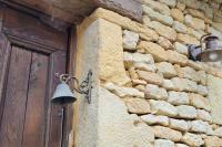 a bell on the side of a stone building with a door at Maison périgourdine avec vue et piscine chauffée in Peyzac-le-Moustier