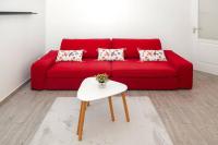 a red couch with pillows and a table in a living room at Appartement cosy à 10 min de Disneyland Paris ! in Montévrain